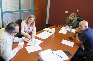 Darcy Davis and John Pacenti discuss the proposal. Chris and Belma sit at the table and listen.